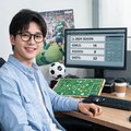 一位戴眼镜的男性足球数据编辑在工作台前微笑